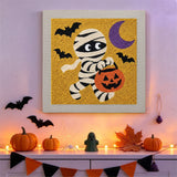 Tableau punch needle momie en balade accroché au mur parmi des décorations d'Halloween