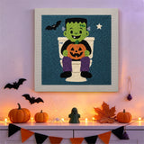 Tableau punch needle monstre aux toilettes accroché au mur dans une déco d'Halloween
