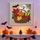 Tableau punch needle panier de récolte et fantôme accroché au mur dans une déco d'Halloween