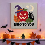Tableau punch needle pomme sorcière accroché au mur dans une cuisine décorée pour Halloween