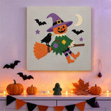 Tableau punch needle épouvantail sur son balai accroché au mur dans une déco d'Halloween