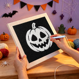 Broderie punch needle en cours, aiguille en main, sur la toile de la citrouille blanche sur fond noir