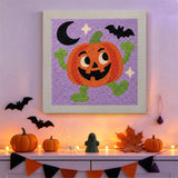 Tableau punch needle citrouille rieuse accroché au mur dans une déco d'Halloween