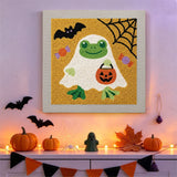 Tableau punch needle grenouille fantôme accroché au mur dans une déco d'Halloween