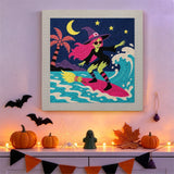 Tableau punch needle sorcière surfeuse accroché au mur dans une déco d'Halloween