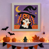 Tableau punch needle sorcière à tête de citrouille accroché au mur dans une déco d'Halloween