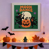 Tableau punch needle sorcière et chat qui dansent accroché au mur dans une déco d'Halloween
