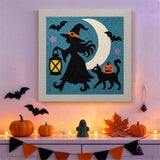 Tableau punch needle sorcière à la lanterne accroché au mur dans une déco d'Halloween