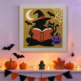 Tableau punch needle sorcière qui lit accroché au mur dans une déco d'Halloween