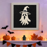 Tableau punch needle spectre blanc sur fond noir accroché au mur dans une déco d'Halloween