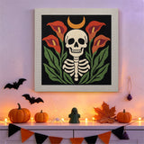 Tableau punch needle squelette aux arums accroché au mur dans une déco d'Halloween