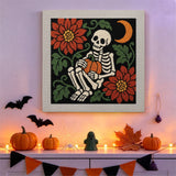 Tableau punch needle squelette et citrouille accroché au mur dans une déco d'Halloween