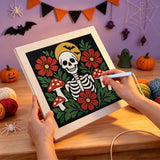 Broderie punch needle en cours sur la toile squelette entouré de fleurs rouges