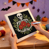 Broderie punch needle en cours, aiguille en main, sur la toile du squelette aux fleurs rouges