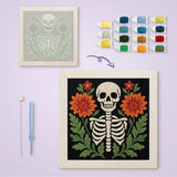 Toile imprimée numérotée et tableau punch needle squelette entre deux fleurs terminé