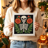 Tableau punch needle squelette encadré de fleurs tenu en main pour montrer sa taille