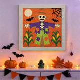 Tableau punch needle épouvantail squelette accroché au mur dans une déco d'Halloween