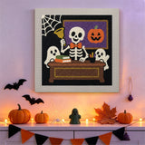 Tableau punch needle squelette professeur accroché au mur parmi des décorations d'Halloween