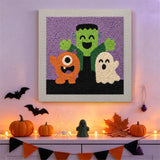 Tableau punch needle trio de monstres accroché au mur dans une déco d'Halloween